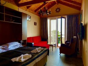 a hotel room with a bed and a red couch at Cottages at Villa Del Mar Kvariati in Kvariat'i