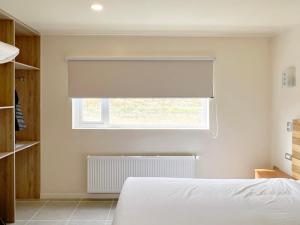 a bedroom with a white bed and a window with a blind at Hotel Casa Verde in Puerto Natales