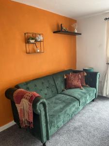 a green couch in a living room with an orange wall at Elite 47 Stays in Newcastle upon Tyne