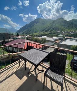 een tafel en 2 stoelen op een balkon met uitzicht op de bergen bij Anano Guest House in Kazbegi