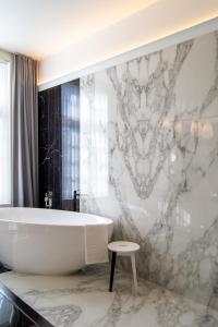 a bath tub in a bathroom with a marble wall at The Old Beech in Antwerp