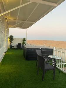 eine Terrasse mit Stühlen und einem Tisch auf dem Rasen in der Unterkunft Desert Inn Resort and Camp in Ras al Khaimah