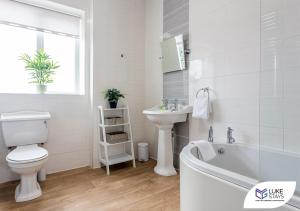een witte badkamer met een wastafel, een toilet en een bad bij Luke Stays - Kitchener Street in Sheriff Hill