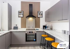 a kitchen with white counter tops and yellow stools at Luke Stays - Kitchener Street in Sheriff Hill