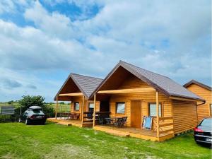 a log cabin with a deck and a car at Domki u strażaka in Jastarnia