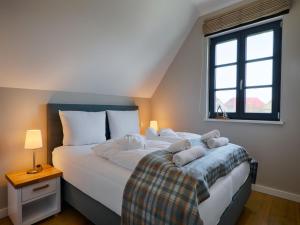 a bedroom with two beds and a window at Reetland am Meer - Premium Reetdachvilla mit 3 Schlafzimmern, Sauna und Kamin F19 in Dranske +12 photos