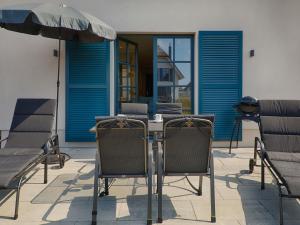 a table with chairs and an umbrella on a patio at Reetland am Meer - Premium Reetdachvilla mit 3 Schlafzimmern, Sauna und Kamin F19 in Dranske