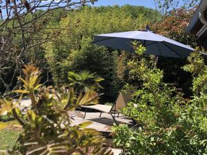 uma mesa e um guarda-sol num jardim em Villa KIKO Spa & Sauna privatifs Gîte proche Sarlat em Vitrac