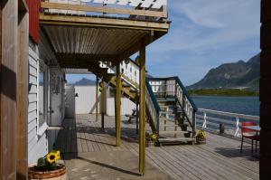 a wooden deck with a staircase next to the water at Lydersen Rorbuer Budget Hostel & Private Apartments in Fredvang