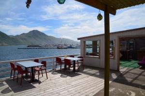 a wooden deck with tables and chairs on the water at Lydersen Rorbuer Budget Hostel & Private Apartments in Fredvang
