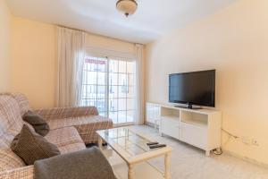 ein Wohnzimmer mit einem Sofa und einem TV in der Unterkunft ESTEPONA BEACHSIDE in Estepona