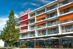 a hotel building with a tree in front of it at Appart-Hôtel Mer & Golf City Bordeaux - Bruges in Bruges