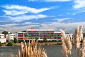 a building with red and white windows and a river at Appart-Hôtel Mer & Golf City Bordeaux - Bruges in Bruges