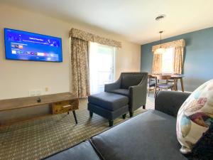 a living room with a couch and a chair and a tv at The Central Downtown Inn Suites in Pittsfield