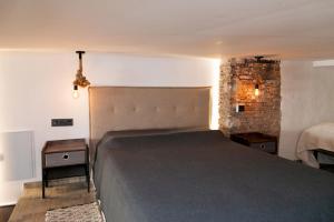 1 dormitorio con 1 cama grande y pared de ladrillo en Apartamentos BocairentHomes, disfruta en pleno centro de Bocairent, en Bocairent