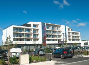 a white building with cars parked in front of it at Appart-Hôtel Mer & Golf City Bordeaux - Bruges in Bruges