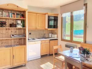 a kitchen with wooden cabinets and a table and a dining room at Appartement Saint-Martin-de-Belleville, 2 pièces, 4 personnes - FR-1-344-246 in Saint-Martin-de-Belleville