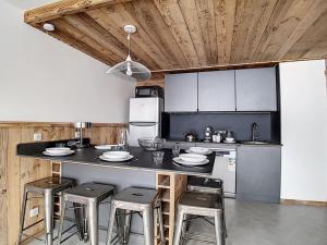 a kitchen with a black counter and stools in it at Appartement Les Menuires, 2 pièces, 5 personnes - FR-1-344-595 in Les Menuires