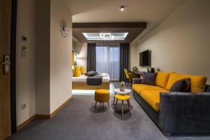 a living room with a yellow couch and a bedroom at EMAR HOTEL & SPA in Sapareva Banya
