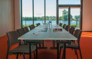 a long table in a room with chairs and windows at Appart-Hôtel Mer & Golf City Bordeaux - Bruges in Bruges