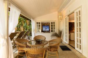 a porch with a glass table and chairs at Rede Reserva Bromélias in Angra dos Reis