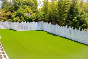una valla blanca en un patio con césped verde en ドッグラン併設 しまなみ御殿, en Imabari