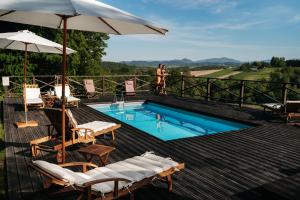 a swimming pool with chairs and an umbrella on a deck at Dwór Sieraków in Sieraków