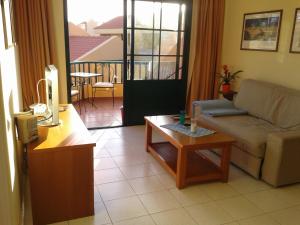 een woonkamer met een bank en een tafel bij Gepflegte Apartment-Anlage mit Pool und Garten in La Playa Calera