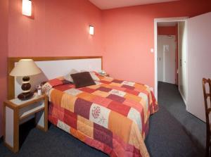 a bedroom with a bed and a table with a lamp at Logis Hotel Restaurant des Voyageurs in Le Malzieu-Ville