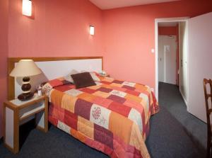 una camera da letto con un letto e un tavolo con una lampada di Logis Hotel Restaurant des Voyageurs a Le Malzieu-Ville Altre 9 foto