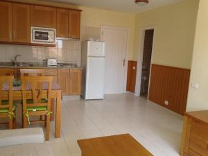 een keuken met een tafel en een witte koelkast bij Gepflegte Apartment-Anlage mit Pool und Garten in La Playa Calera