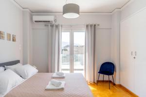 a white bedroom with a bed and a blue chair at Penthouse in the heart of Athens / Koukaki area in Athens