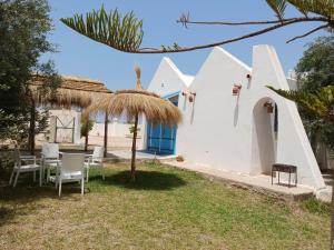 Casa blanca con mesa y sillas en el patio en Nouveau Bungalow Djerba en Houmt El Souk