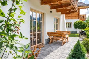 a patio with a wooden bench and a table at Chaletdorf am Sonnenhang in Neukirchen am Großvenediger