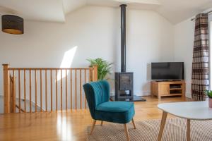 a living room with a blue chair and a tv at Modern, well placed house walkable to beach & town in Lyme Regis