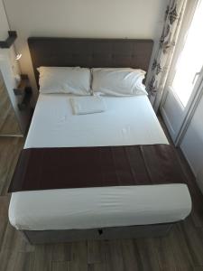 um quarto com uma cama com um lençol branco e uma janela em villa alex em Toulouse