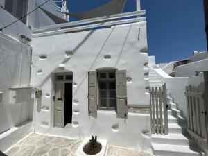 a white building with gray doors and a potted plant at Cycladic Rooftop House in the Heart of Parikia in Parikia