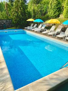 a large blue swimming pool with chairs and umbrellas at Appartementhaus 5. Jahreszeit in Hévíz