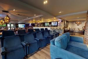 uma sala de espera com cadeiras azuis e um bar em Village Hotel Bournemouth em Bournemouth