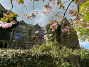 uma velha casa de pedra com flores cor-de-rosa à frente. em Riber Hall Manor em Matlock Bank