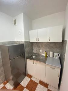 een keuken met een roestvrijstalen koelkast en witte kasten bij Apartman Citylux in Bihać