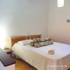 una camera da letto con un letto con lenzuola e cuscini bianchi di Corsário Hotel a Ubatuba