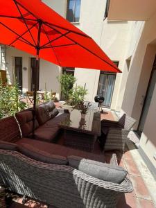 a patio with a couch and a red umbrella at Gästewohnung in Halle an der Saale