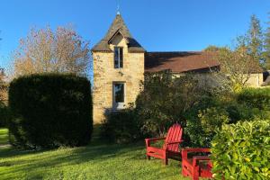 two red benches sitting in front of a house at Le Petit Manoir de Vitrac in Vitrac