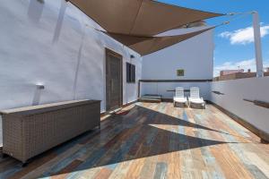 un balcone con 2 sedie bianche e un ombrellone di Dimore Italiane - Boutique Apartments a Corralejo