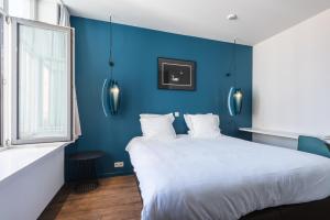 Dormitorio azul con cama blanca y pared azul en Zakske13 - Design Boutique B&B in Bruges city centre, en Brujas