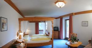 a bedroom with a canopy bed with a window at Sport Hotel Wildgall in Anterselva di Mezzo