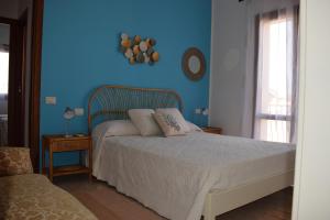 a bedroom with a bed with a blue wall at Casa rosa dei venti in Pula