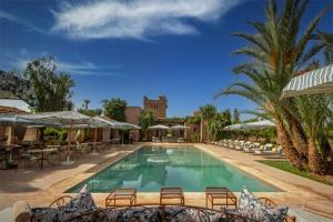a pool at a resort with chairs and umbrellas at Villa Nour in Marrakesh