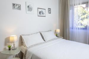 a white bedroom with a white bed and two tables at Apartments Mario 2 in Pula